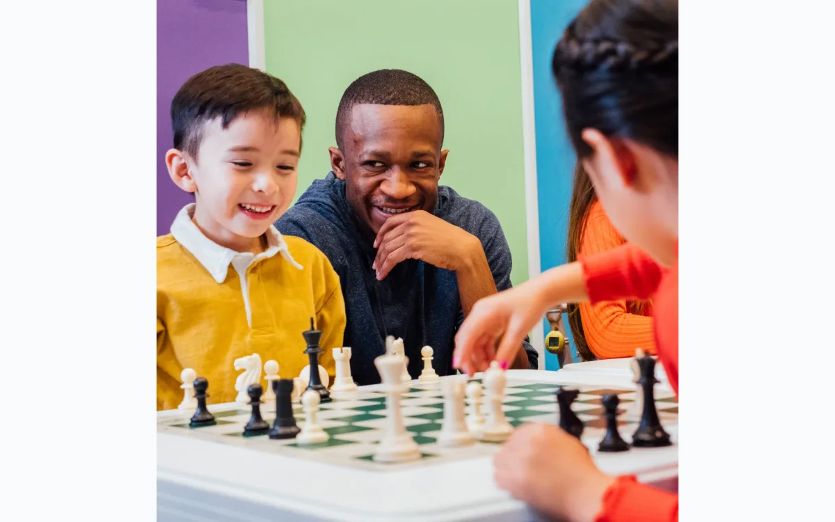 Children learning chess with a friendly coach in a colorful classroom environment